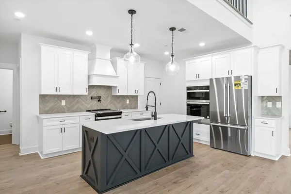 The Smokey kitchen with a black X-panel island, white cabinets, and a stainless refrigerator