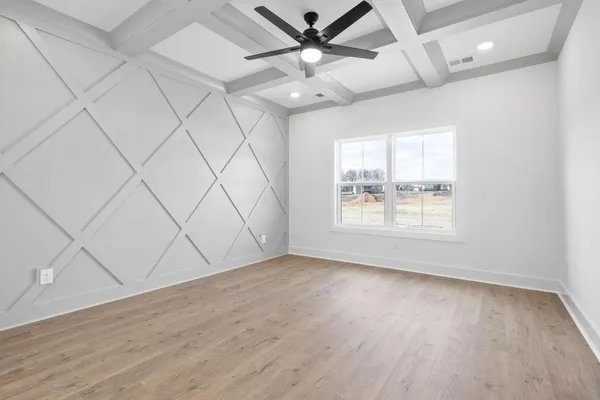 The Smokey bedroom with a diamond trim accent wall, a coffered ceiling, and a ceiling fan