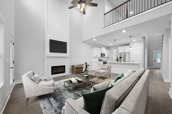 The Brayden living room staged with a sectional under a two-story ceiling with a loft railing above