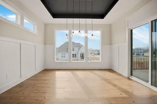 Wood-finish flooring, wainscoting wall accents, multiple large windows, sliding glass door, and a recessed ceiling with integrated lighting fixtures