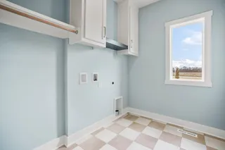 Utility room featuring checkerboard flooring, white cabinetry, a built-in hanging rod, and a window with a rural backdrop