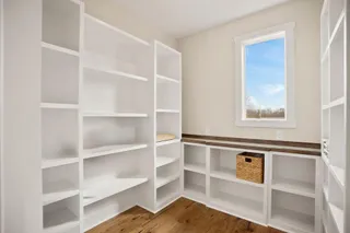 Extensive built-in shelving, wood-finish flooring, and a single window with white trim