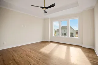 Tray ceiling with crown molding, contemporary ceiling fan, and wood-finish flooring