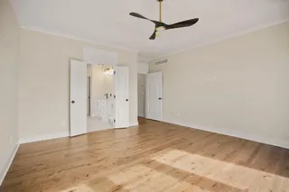 Wood-finish flooring throughout, paired with a ceiling fan featuring a gold-tone fixture
