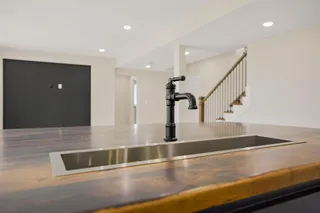 Kitchen island with a built-in linear sink, matte black faucet, and recessed lighting