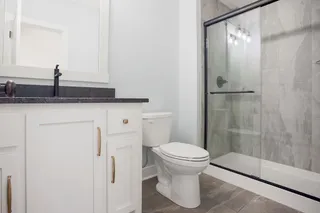 White vanity with brass hardware, dark countertop, and integrated sink