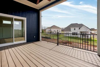 Covered outdoor deck with composite decking, black metal railing, and blue vertical siding