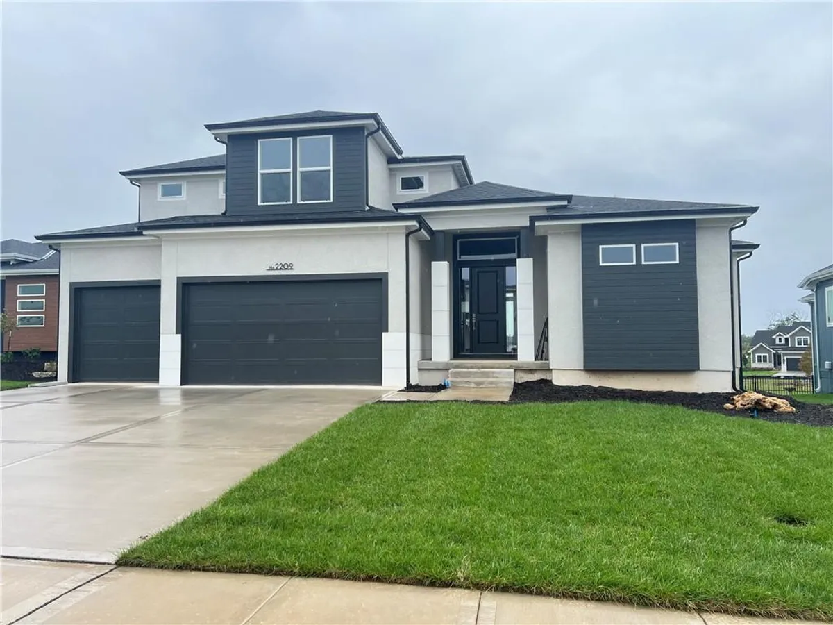 Clean lines and a spacious concrete driveway define this modern two-story home design.