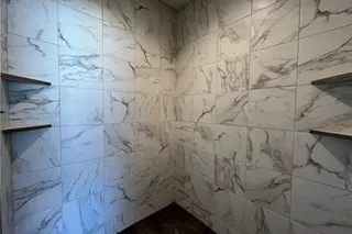 Elegantly tiled walls pair with sleek built-in shelving in this modern walk-in shower with 2 Shower Heads. Primary Shower with Designer tiled walls to the ceiling, tiled floor, built shelving and 2 Shower Heads. Home Under  Construction. OCTOBER 2026 COMPLETION, PHOTO IS OF ACTUAL HOME.