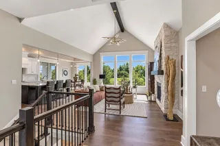 A stone fireplace anchors the soaring living space framed by rich wood floors. PHOTO IS OF ACTUAL HOME.