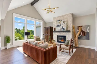 Soaring vaulted ceilings and a stone fireplace anchor this warm living space with hardwood floors. PHOTO IS OF ACTUAL  HOME.
