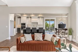 An open floor plan seamlessly connects the main living spaces beneath vaulted ceilings. PHOTO IS OF ACTUAL HOME.