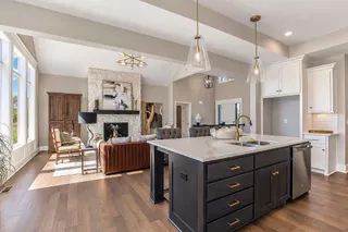 Hardwood floors and a stone fireplace anchor this open-concept layout with vaulted ceilings. PHOTO IS OF ACTUAL  HOME.