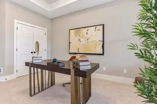 Double doors open into a quiet workspace featuring recessed ceiling details and neutral carpeting. PHOTO IS OF ACTUAL  HOME.