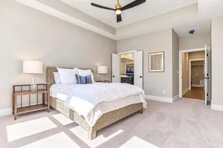 Plush carpet underfoot pairs with a tray ceiling and double doors leading to the bath.