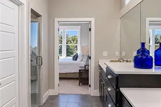 Polished tile flooring and quartz countertops highlight this modern primary bathroom suite.