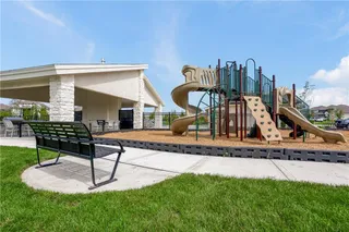 An inviting community park offers a modern playground structure alongside a covered stone pavilion.