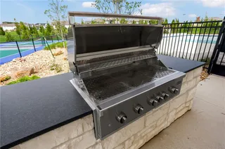 A built-in stone grilling station overlooks the adjacent sports court.