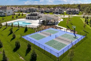 An aerial perspective showcases a modern neighborhood amenity center featuring sports courts and a swimming pool.