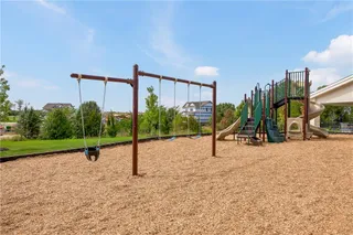 An expansive outdoor play area features a comprehensive playground set over a wood chip surface.