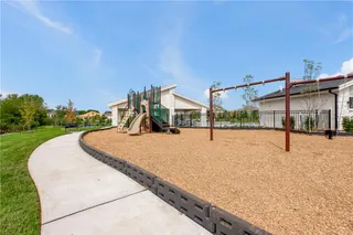 A curved concrete walkway leads past a well-maintained neighborhood playground with a mulched play area.