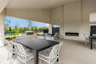 An expansive covered patio features a built-in stone fireplace and outdoor kitchen setup.