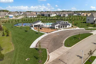 An aerial view showcases a vibrant community park featuring a playground, pool, and sports courts.