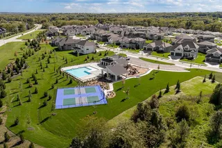 A vibrant neighborhood recreation center features a shimmering pool and basketball courts amidst green lawns.
