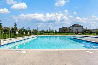 An inviting community swimming pool sits under clear blue skies near neighborhood homes.