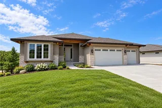 A spacious driveway leads to this modern Reverse-style home featuring stone accents. PHOTO IS OF ACTUAL HOME. LANDSCAPE SHRUBS, FLOWERS AND SOD ARE VIRTUALLY STAGED.