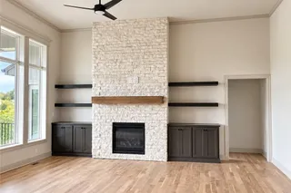 A floor-to-ceiling stone fireplace serves as the centerpiece of this light-filled room. PHOTO IS OF ACTUAL HOME.