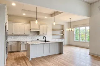 Gleaming hardwood floors and upgraded quartz countertops black composite sink, lower cabinets and floating shelves in the Dining Room define this open-concept kitchen and adjacent dining area. PHOTO IS OF ACTUAL HOME