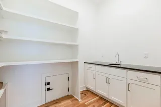 Photo of actual home. Walk-in pantry with sink and grocery door.