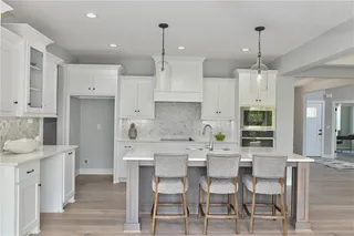 PICTURE IS OF THE ACTUAL HOME. KITCHEN FEATURES LARGE ISLAND WITH GRANITE COUNTERTOPS AND WHITE PAINTED CABINETS, PENDANT LIGHTING, GORGEOUS TILE BACKSPLASH.