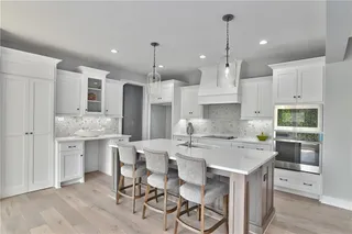 PICTURE IS OF THE ACTUAL HOME. KITCHEN FEATURES LARGE ISLAND WITH GRANITE COUNTERTOPS AND WHITE PAINTED CABINETS.