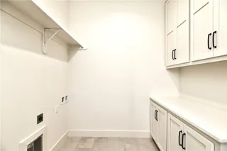 PICTURE IS OF ACTUAL HOME - Space and Storage in this expansive Laundry Room which Connects to Primary Closet. Hanging Shelf above Washer & Dryer, Folding table, lower cabinets and upper cabinets to the ceiling.