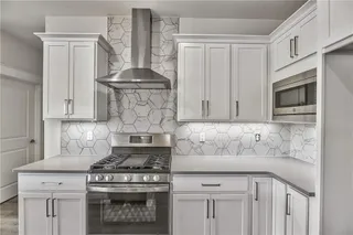 The Colton Reverse. Pictures are of the actual home. Close up of the beautiful kitchen with hexagon backsplash, white cabinets, stainless appliances, and quartz countertops. Note the gas stove.