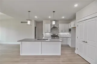 Pictures are of the actual home. Pantry doors just next to the refrigerator space. Island has breakfast bar. Stainless appliances including gas stove.