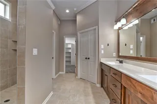 Primary bathroom includes a huge shower, two sinks, wood trim around mirror, nice size closet and laundry access.
