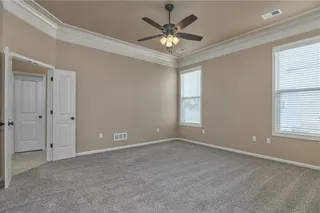 Large primary bedroom has double doors and ceiling fan.