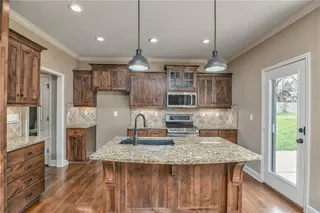 Large kitchen island with a breakfast bar, granite counter tops, and stainless appliances.  Patio door walks out to the backyard oasis with an outdoor kitchen!