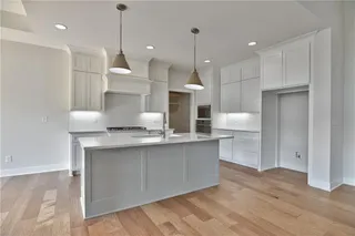 Pictures are of a Previous Model AND MAY FEATURE UPGRADES. SEVERAL BUYER SELECTIONS ARE STILL AVAILABLE. PLEASE CONTACT LISTING AGENT FOR DETAILS.Kitchen featuring light hardwood / wood-style floors, pendant lighting, tasteful backsplash, and oven