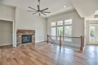 Pictures are of a Previous Model AND MAY FEATURE UPGRADES. SEVERAL BUYER SELECTIONS ARE STILL AVAILABLE. PLEASE CONTACT LISTING AGENT FOR DETAILS.Unfurnished living room with a high ceiling, a stone fireplace, ceiling fan, and light hardwood / wood-style flooring