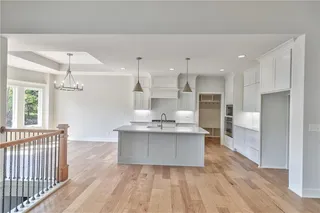 Pictures are of a Previous Model AND MAY FEATURE UPGRADES. SEVERAL BUYER SELECTIONS ARE STILL AVAILABLE. PLEASE CONTACT LISTING AGENT FOR DETAILS.Kitchen featuring pendant lighting, white cabinetry, backsplash, oven, and an inviting chandelier