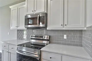View of Kitchen/Dining Room. Upgraded Quartz Counter Tops, Modern Light Fixtures, Stainless Steel Appliances, Walk in Pantry and Hard Wood Floors. Access to Deck is from Dining Room. Picture is of Actual Home. 