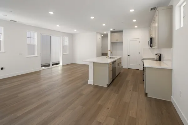 Open kitchen and dining area with center island, large windows and sliding glass door.