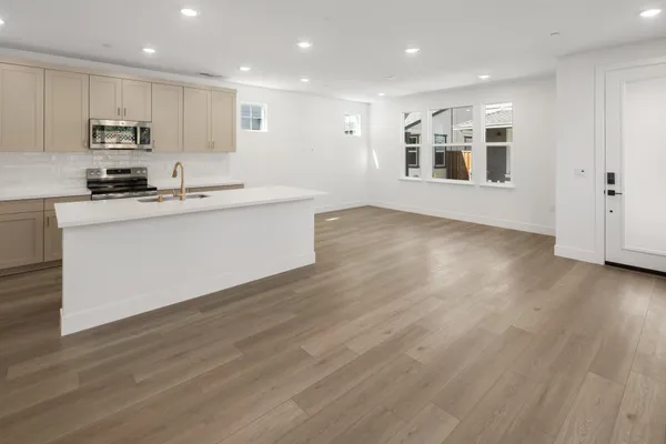 Open kitchen and great room with center island, large windows and luxury vinyl plank flooring.