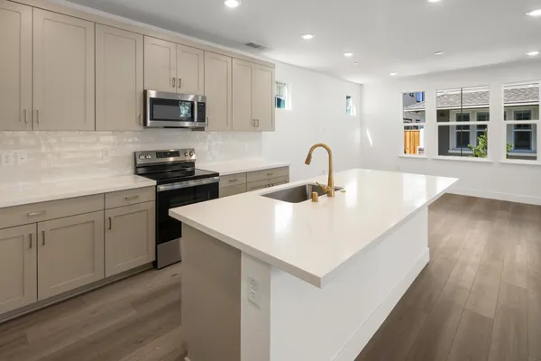 Kitchen with large center island, light cabinetry and stainless steel appliances.