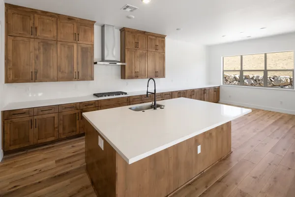 Kitchen with a large island, stainless steel range hood, and adjoining dining area.