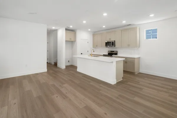 Open-concept kitchen and great room with center island, light cabinetry and recessed lighting.